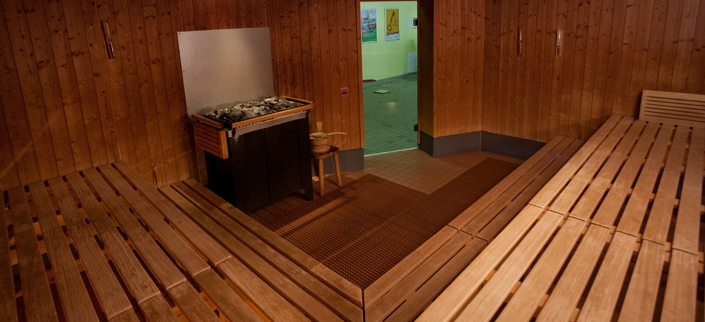 Innenansicht einer Sauna mit Blick auf den Ofen und Aufguss