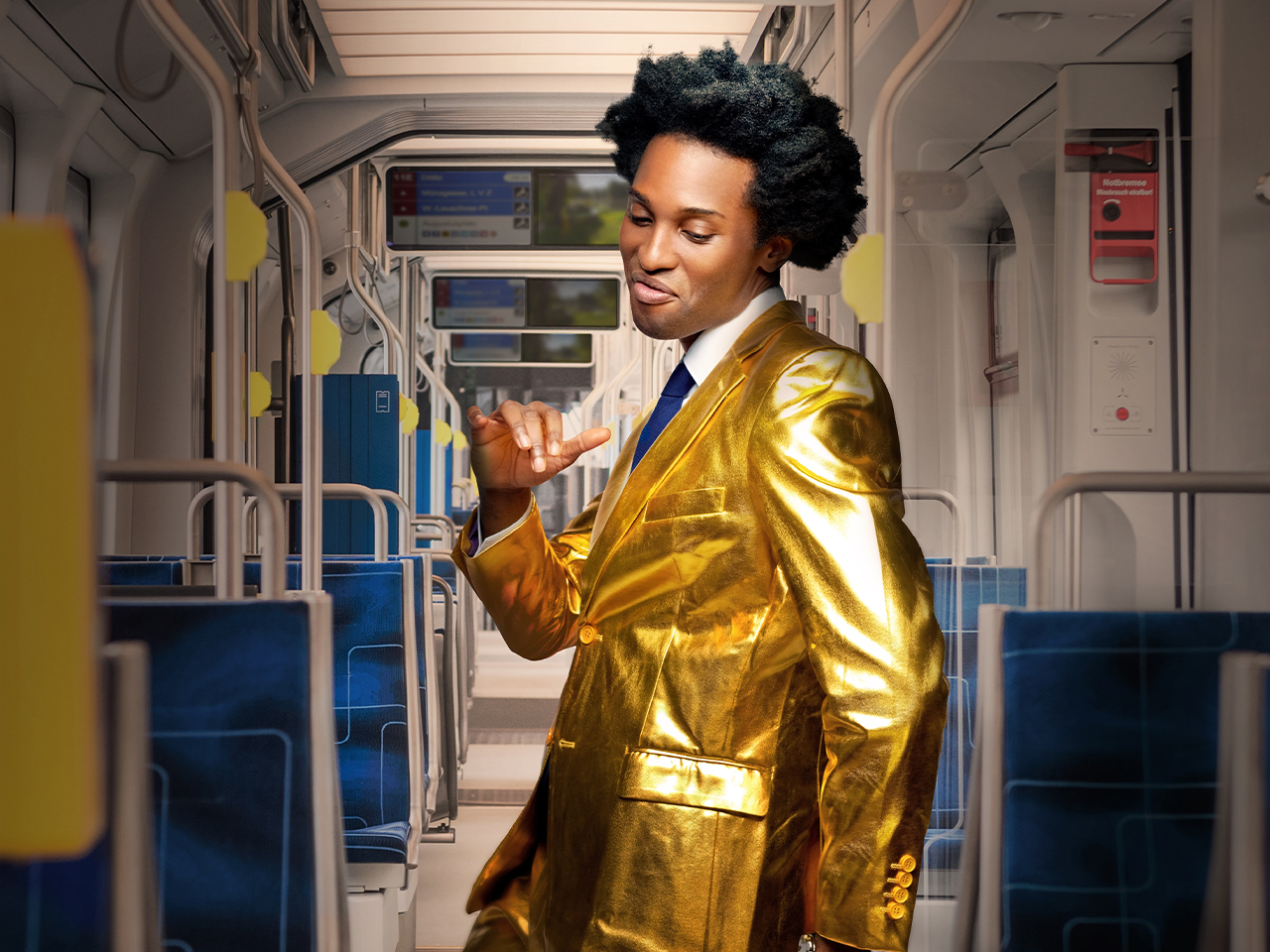 Das Bild zeigt einen Mann in einer Straßenbahn der LVB. ER trägt einen goldenen Anzug und tanzt.