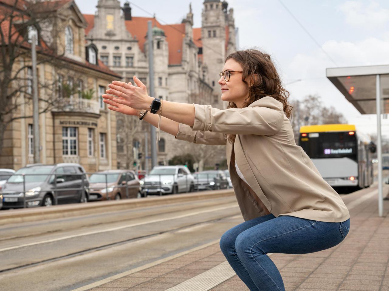 Eine junge Frau macht Kniebeugen an einer Halstestelle der LVB