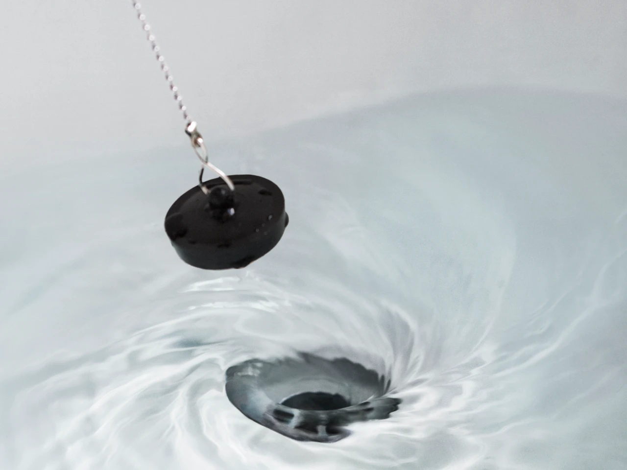 Ein Stöpsel wird aus einem vollen Waschbecken gezogen.